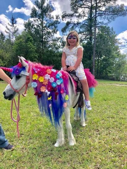 Princess, a beautiful rainbow unicorn giving rides at a birthday in Jacksonville, FL.